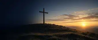 A wooden cross on a hill at sunrise, illustrating theories of the atonement